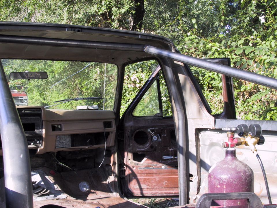 Stripped truck cab interior with roll bar and gas bottle, viewed through open doorway
