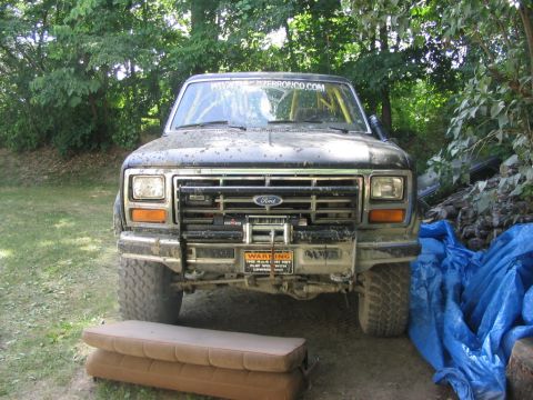 1986 Ford Bronco - Front view of a 1986 Ford Bronco, showing its grille, winch, and a website sticker on the windshield.