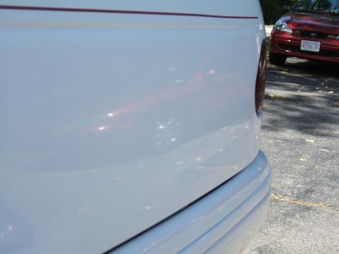 1998 Ford Taurus - A white car's rear quarter panel is shown, with a red car in the background.