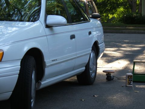1998 Ford Taurus - Side view of a white 1998 Ford Taurus, parked outdoors with cleaning supplies nearby.
