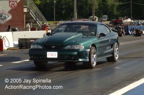 1995 Ford Mustang - A green 1995 Ford Mustang is positioned on a drag strip, ready for a race.