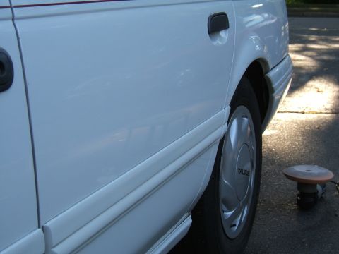 1998 Ford Taurus - A white sedan's side profile is visible, with a polishing tool nearby on the pavement.