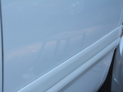 1998 Ford Taurus - Close-up of white car door molding, showing reflections of windows in the paint.