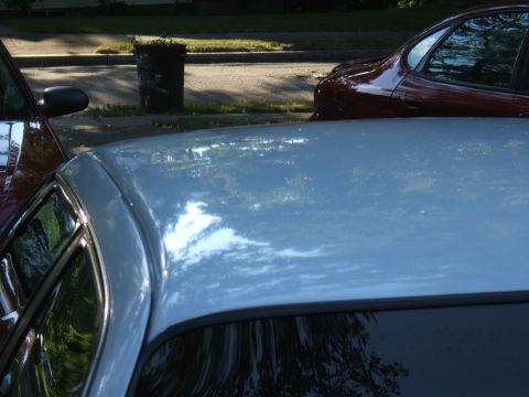 1998 Ford Taurus - Two cars are parked on a street next to a sidewalk and a trash can.