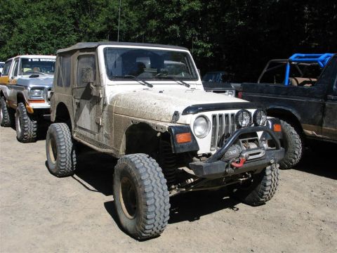 1989 Dodge Power Ram - Modified Jeep Wrangler TJ and other off-road vehicles parked on a dirt lot.