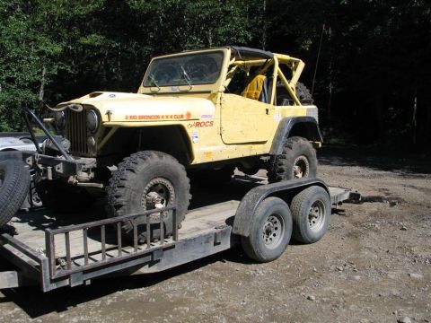 1989 Dodge Power Ram - A yellow Jeep CJ-7, modified for off-roading, is loaded onto a trailer, ready for transport.
