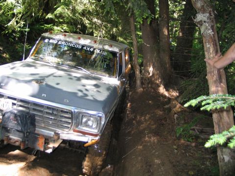 1989 Dodge Power Ram - This pickup truck, possibly a Ford, is seen navigating a challenging wooded trail, with a club sticker visible on the windshield.