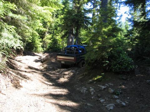 1989 Dodge Power Ram - A 1989 Dodge Power Ram navigates a challenging off-road trail through a dense forest.