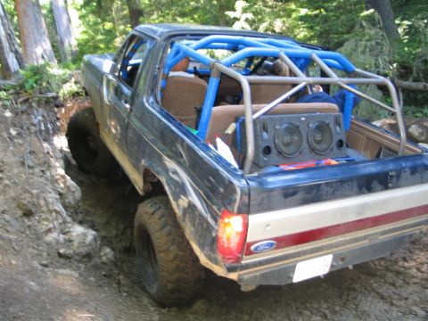 1989 Dodge Power Ram - Modified 1989 Dodge Power Ram navigating a steep, muddy off-road trail with a custom roll cage and speakers.