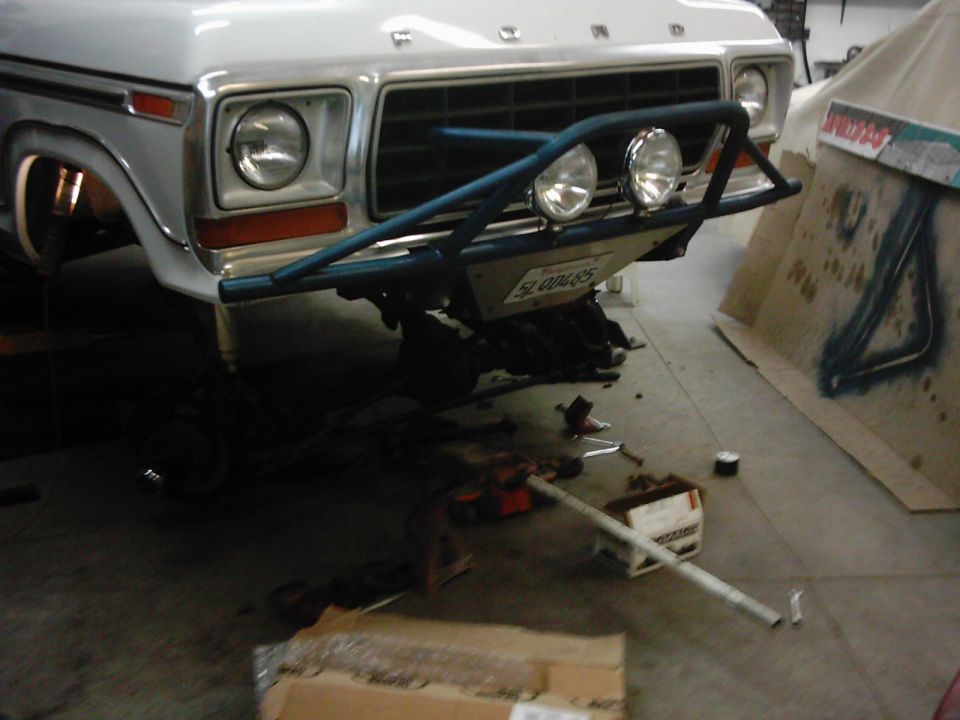 1978 Ford Bronco front end with blue custom bumper and auxiliary lights, undergoing repairs