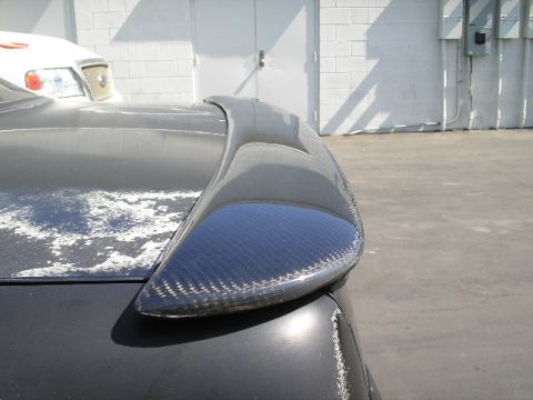 1991 Ford Taurus - Close-up of a carbon fiber rear spoiler on a car trunk with damaged paint.