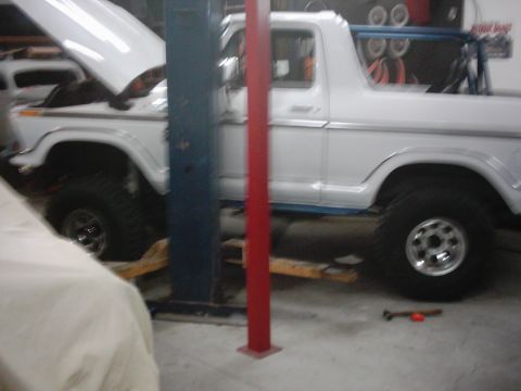 1978 Ford Bronco - A white 1978 Ford Bronco is shown on a lift in a garage, with its hood raised.