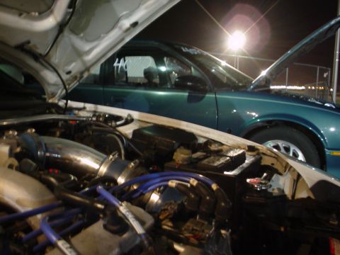 1993 Ford Probe - Two cars are parked with their hoods open, revealing engine bays and components under artificial lighting.