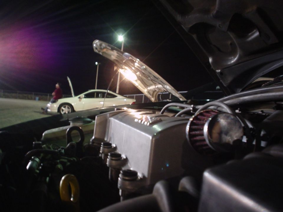 Engine bay with custom intake, white car in background