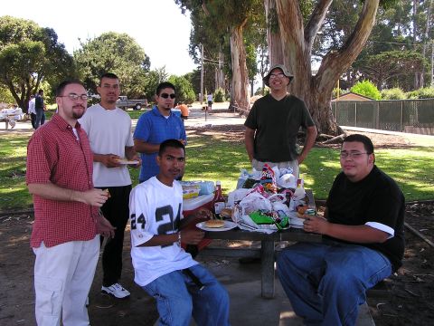 1993 Ford Taurus - A group of friends enjoys a picnic lunch outdoors under large trees.