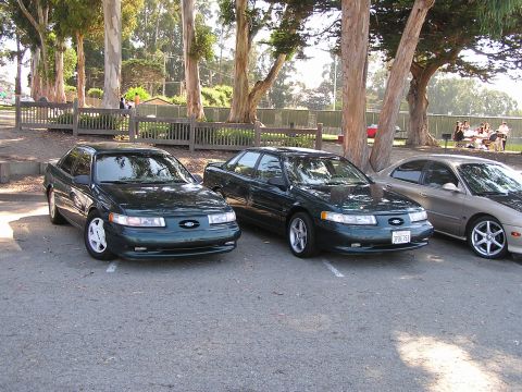 1993 Ford Taurus - Three sedans parked outdoors, two of which appear to be Ford Taurus models from the mid-1990s.