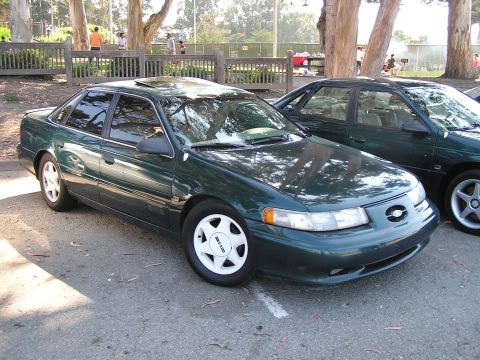 1993 Ford Taurus - Two dark green 1993 Ford Taurus sedans are parked next to each other outdoors.
