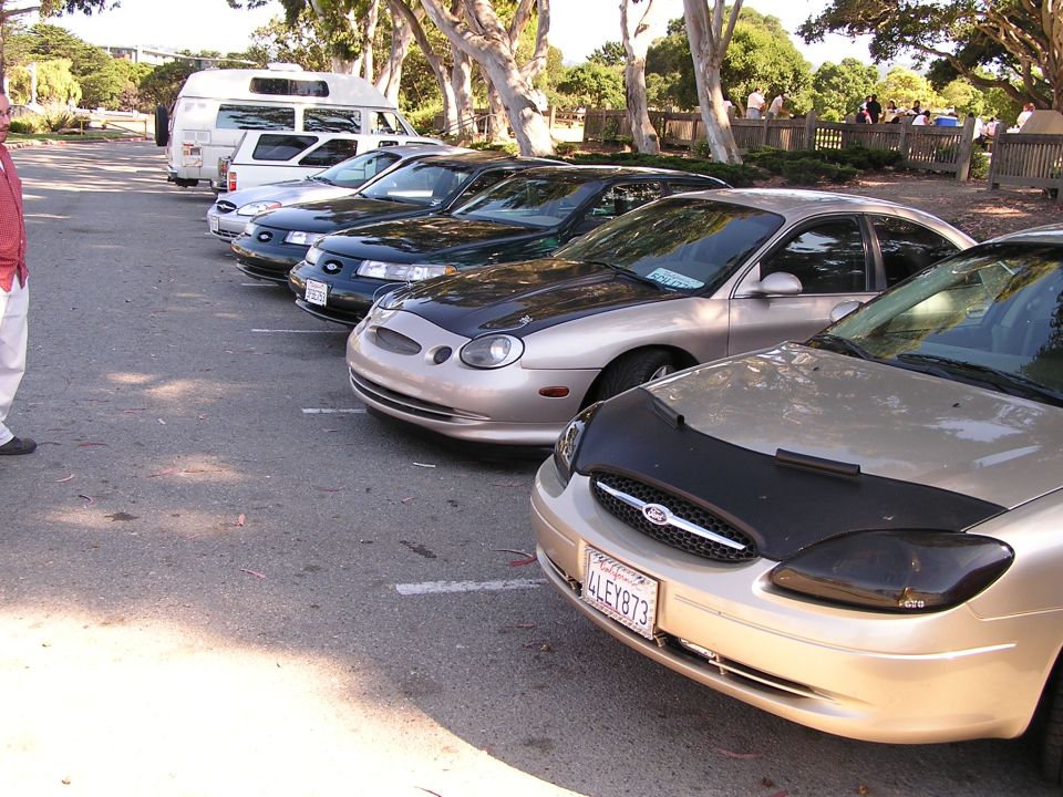 Gold Ford Taurus with a black car bra and tinted headlights, parked in a lot