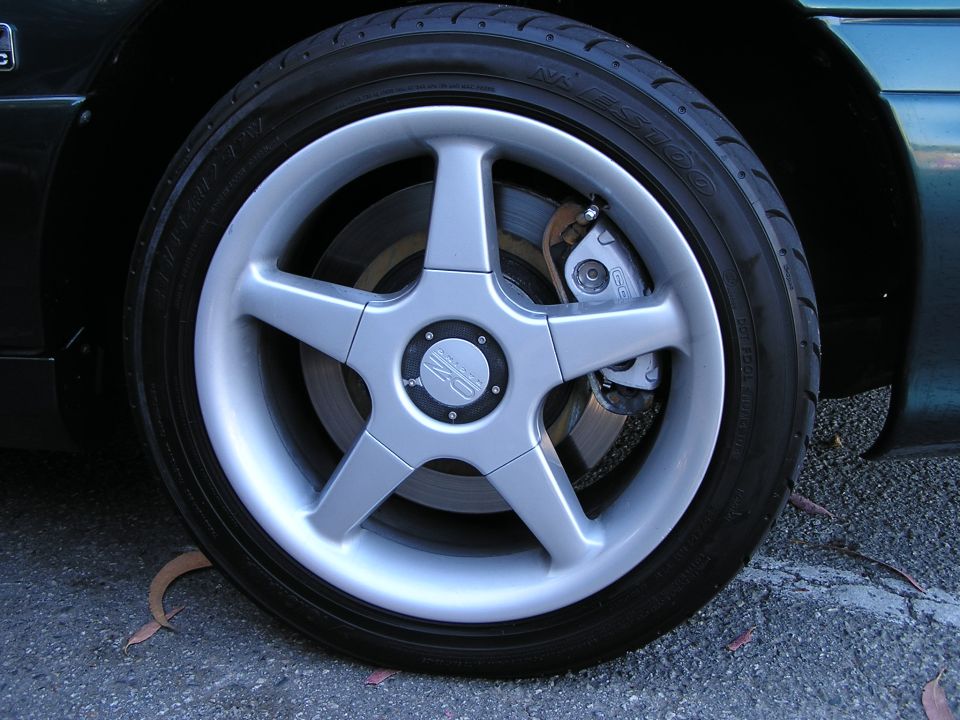 Close-up of a silver five-spoke wheel with a "OZ" center cap and performance brake caliper