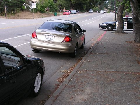 1993 Ford Taurus - A gold sedan is parked on the side of the road, with a police car visible behind it.