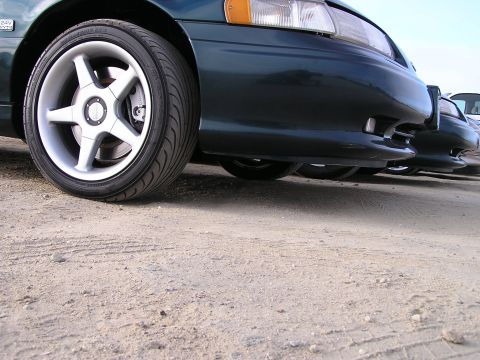 1993 Ford Taurus - Front view of a 1993 Ford Taurus with custom wheels, parked alongside another vehicle.