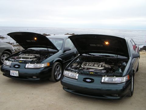 1993 Ford Taurus - Two 1993 Ford Taurus SHO models are displayed with their hoods open, parked near the ocean.