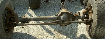 1995 Ford Bronco - Close-up view of a vehicle's front axle, showing the differential, steering linkage, and brake assemblies.