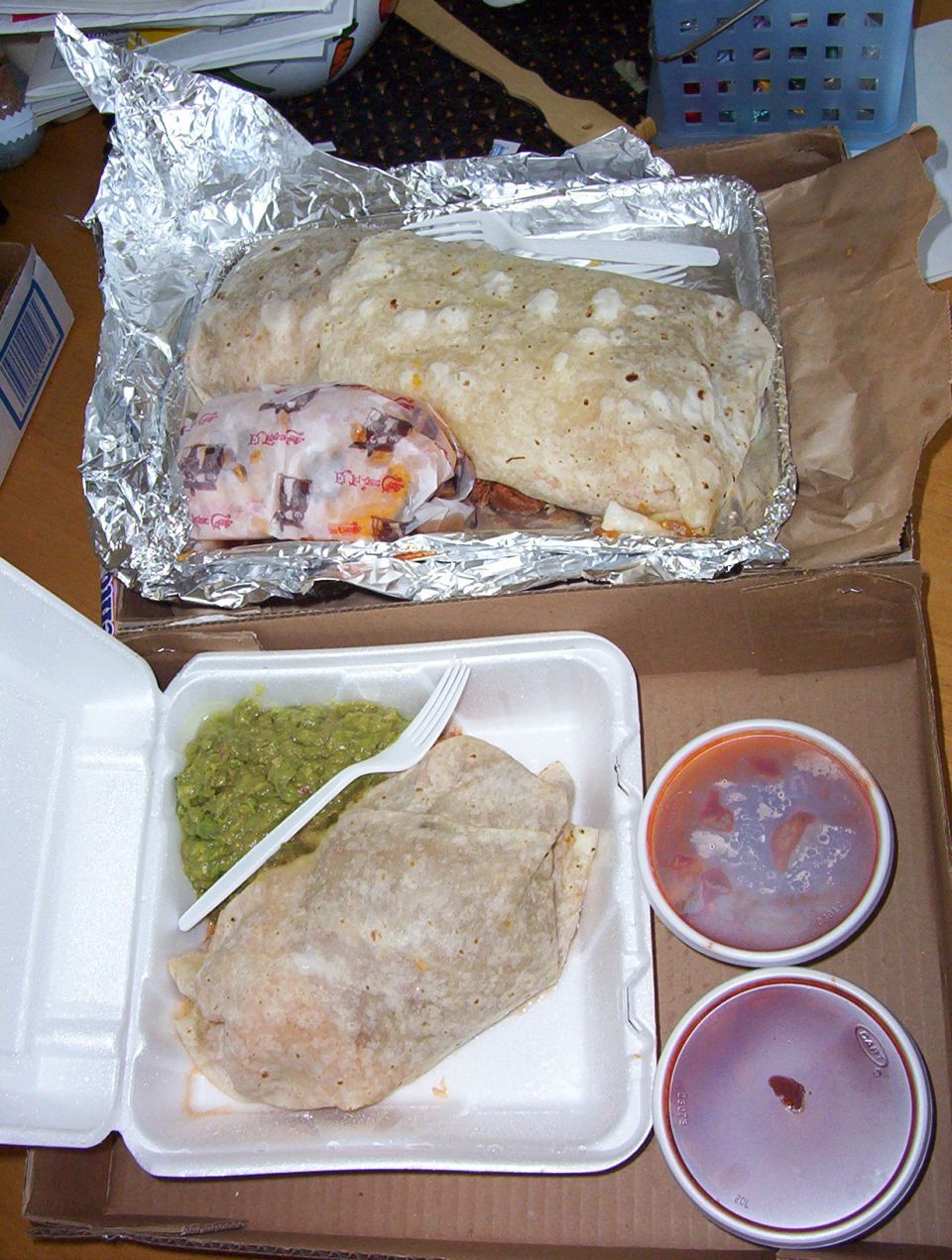Burritos and guacamole in takeout containers