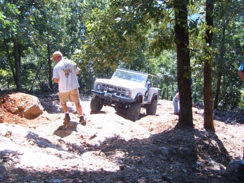 1988 Ford Bronco - A white Ford Bronco tackles a challenging off-road course on a sunny day.