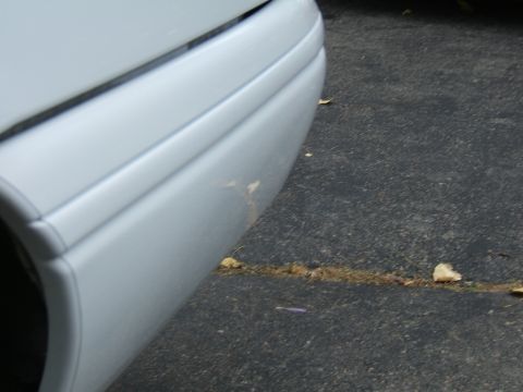 1998 Ford Taurus - Detail of a white car's bumper, showing a small scuff on the painted surface.