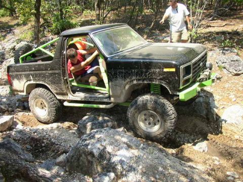 1995 Ford Bronco - Off-road truck with custom roll cage navigates a rocky trail.