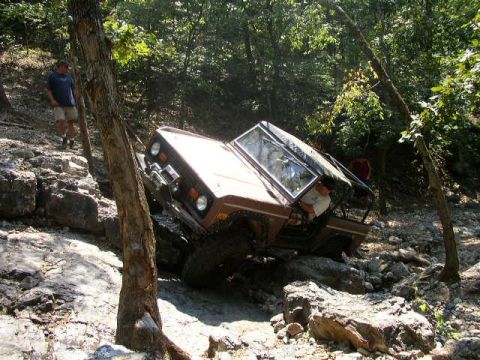 1995 Ford Bronco - This off-road vehicle is navigating a difficult rocky path in a wooded area.