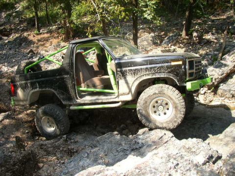 1995 Ford Bronco - This modified truck, likely from the early 1980s, navigates a challenging rocky trail.