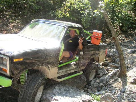 1995 Ford Bronco - Driver poses in a heavily modified off-road truck on a challenging rocky path.