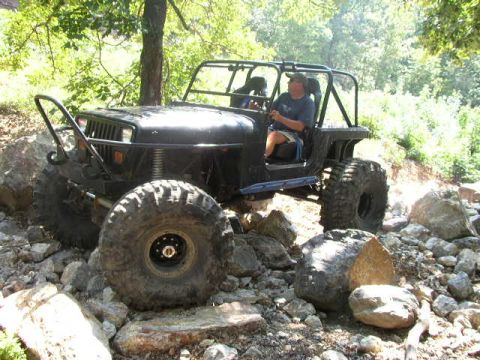1995 Ford Bronco - A black Jeep Wrangler navigates a rocky terrain off-road.