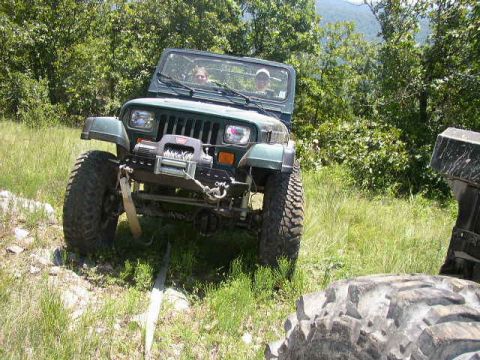 1995 Ford Bronco - Two people in a Jeep Wrangler navigate an off-road trail with another vehicle nearby.