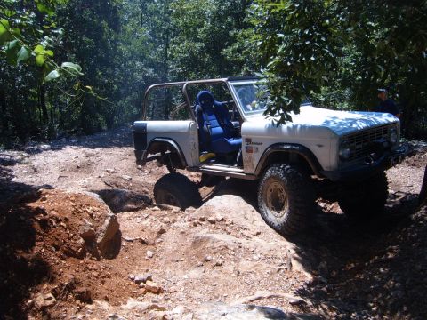 1988 Ford Bronco - This classic Ford Bronco is tackling a challenging off-road trail with large rocks and dirt mounds.