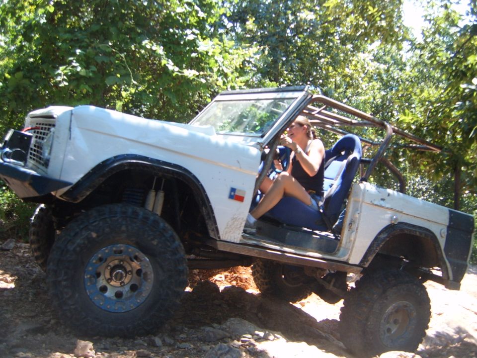 White off-road SUV with a roll cage and off-road tires, viewed from the front-left
