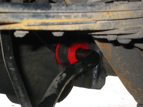 1990 Ford Bronco - Red sway bar bushings are visible, mounted on a black sway bar, with leaf springs above.