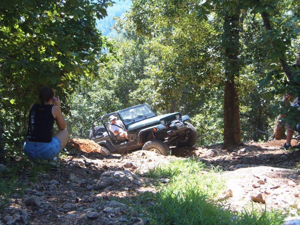 Jeep Wrangler climbing a steep dirt hill with a person watching