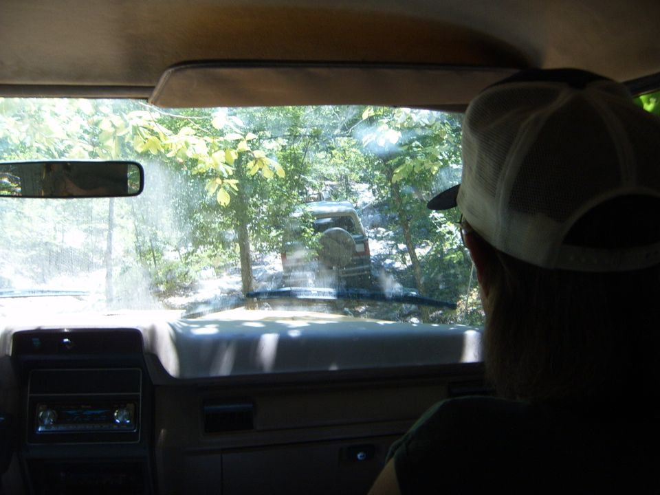 Off-road vehicle with spare tire on rear, driving through trees