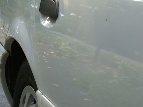 1998 Ford Taurus - Side view of a car's rear wheel arch and door handle.