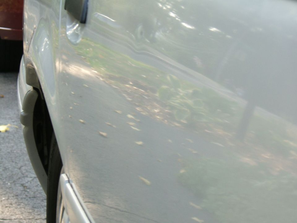 Close-up of a light-colored car door and part of the front wheel well. Watermark reads SUPERMOTORS