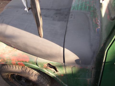 1973 Jeep CJ5 - Close-up of a 1973 Jeep CJ5 fender showing rust damage and a hood with primer applied.