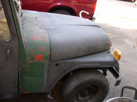 1973 Jeep CJ5 - A partially restored Jeep CJ5 sits next to a red pickup truck.