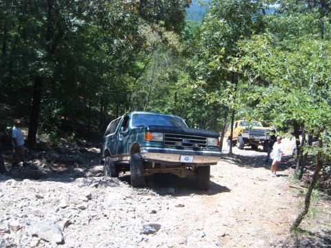 1988 Ford Bronco - This green SUV navigates a rough, rocky path with another truck visible in the background.