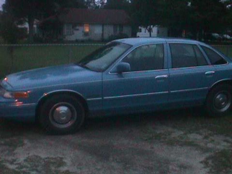 1994 Ford Crown Victoria - A blue sedan is parked outdoors, viewed from its side. The vehicle's body style suggests a 1992 model year.
