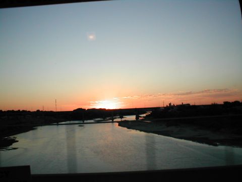1979 Ford Bronco - Sunset over a river with a bridge in the distance, water reflects the sky.