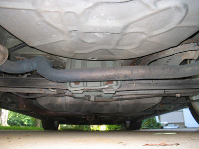 1995 Ford Taurus - The undercarriage of a vehicle is shown, revealing the exhaust pipe and fuel tank.