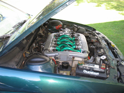 1995 Ford Taurus - The engine bay of a green car is open, revealing a V8 engine with distinctive green intake runners.